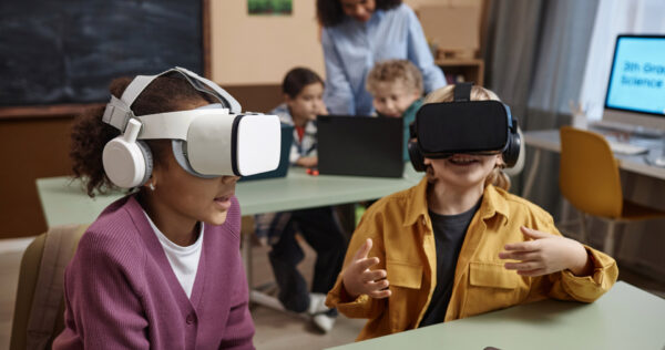 Portrait of two children wearing VR headsets in class and enjoying immersive learning