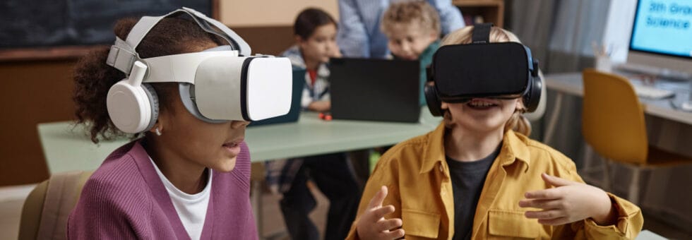 Portrait of two children wearing VR headsets in class and enjoying immersive learning